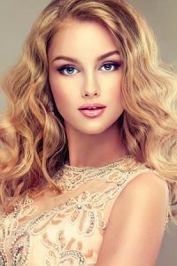 Young beautiful woman, dressed in evening gown. Loose,wavy hair and bright make up.